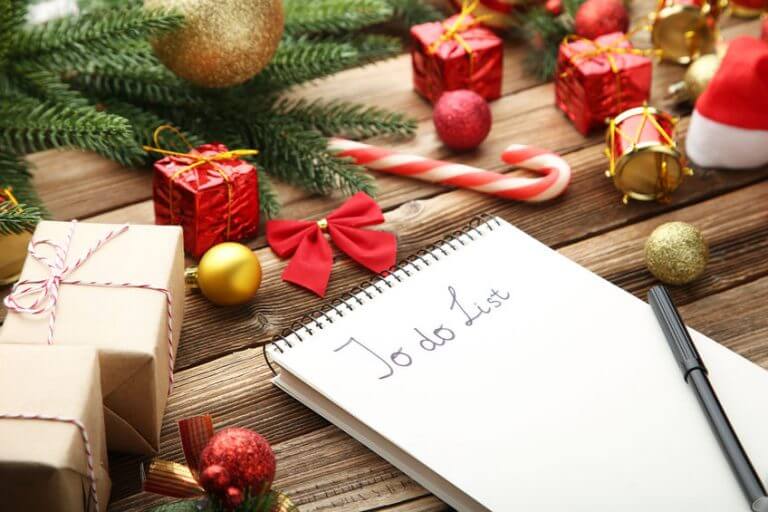 To do list in notepad with christmas decorations on wooden table