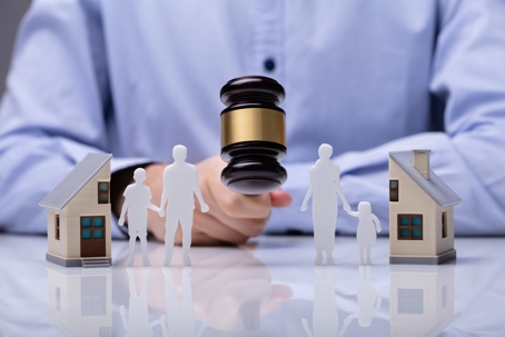 judge banging gavel between figures of a family and house
